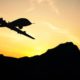 Photo of a military drone silhouette against a sunset